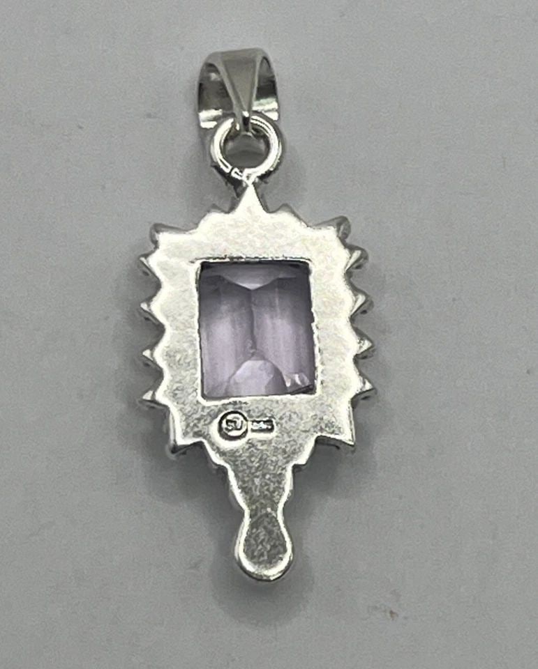 STERLING SILVER & PURPLE EMERALD CUT STONE PENDANT: STERLING SILVER & PURPLE EMERALD CUT STONE PENDANT STERLING SILVER & PURPLE EMERALD CUT STONE PENDANT This pendant features an emerald cut purple stone set in a sterling silver frame, showcasing a sty