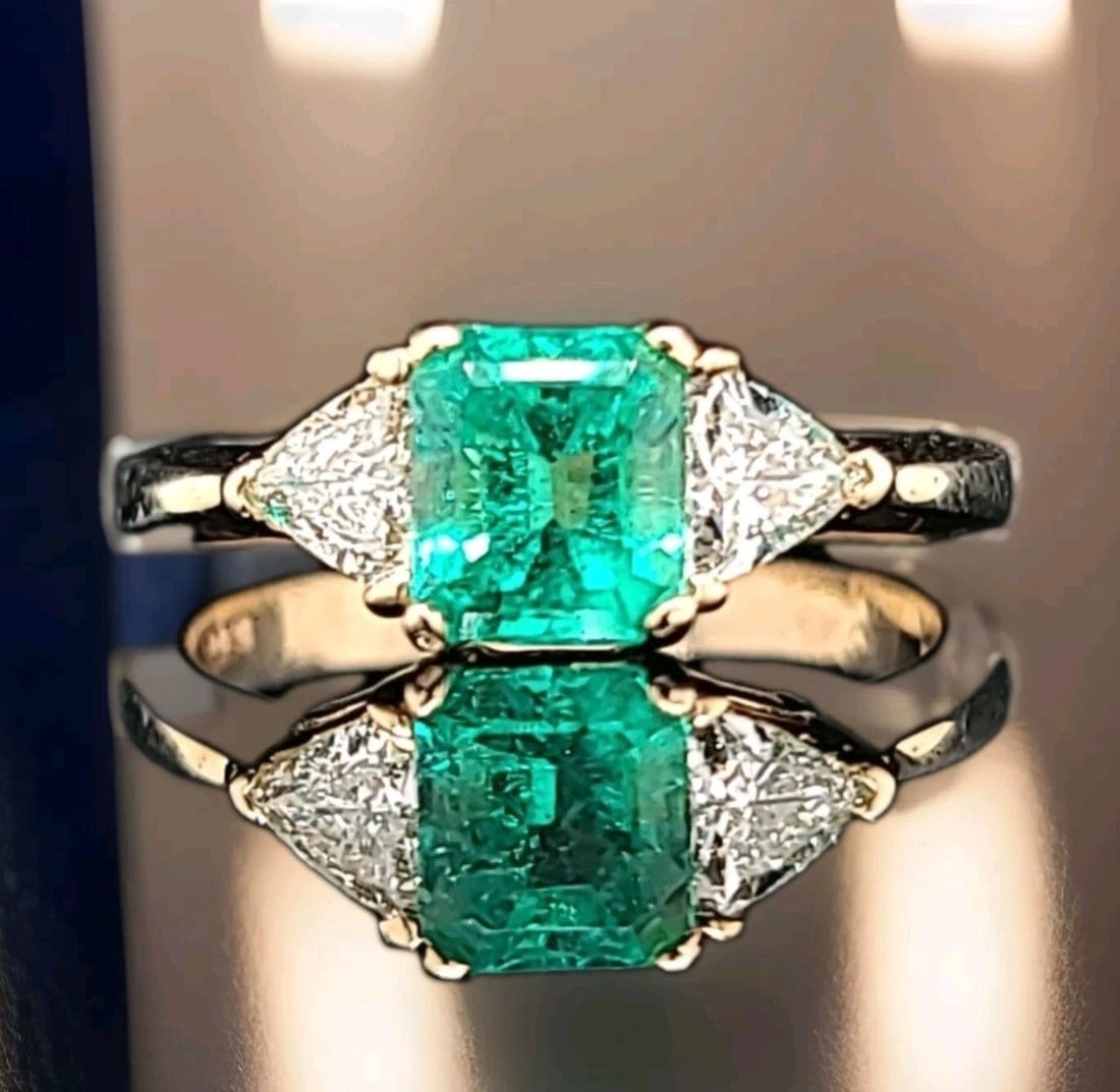Vintage 14K Yellow Gold Engagement Ring 1.02CT.Natural Colombia Emerald Cut: This Vintage 14K Yellow Gold Engagement Ring features a stunning 1.02CT Natural Colombia Emerald Cut emerald as the main stone, surrounded by two trillion-shaped diamonds. The ring is designed in a co