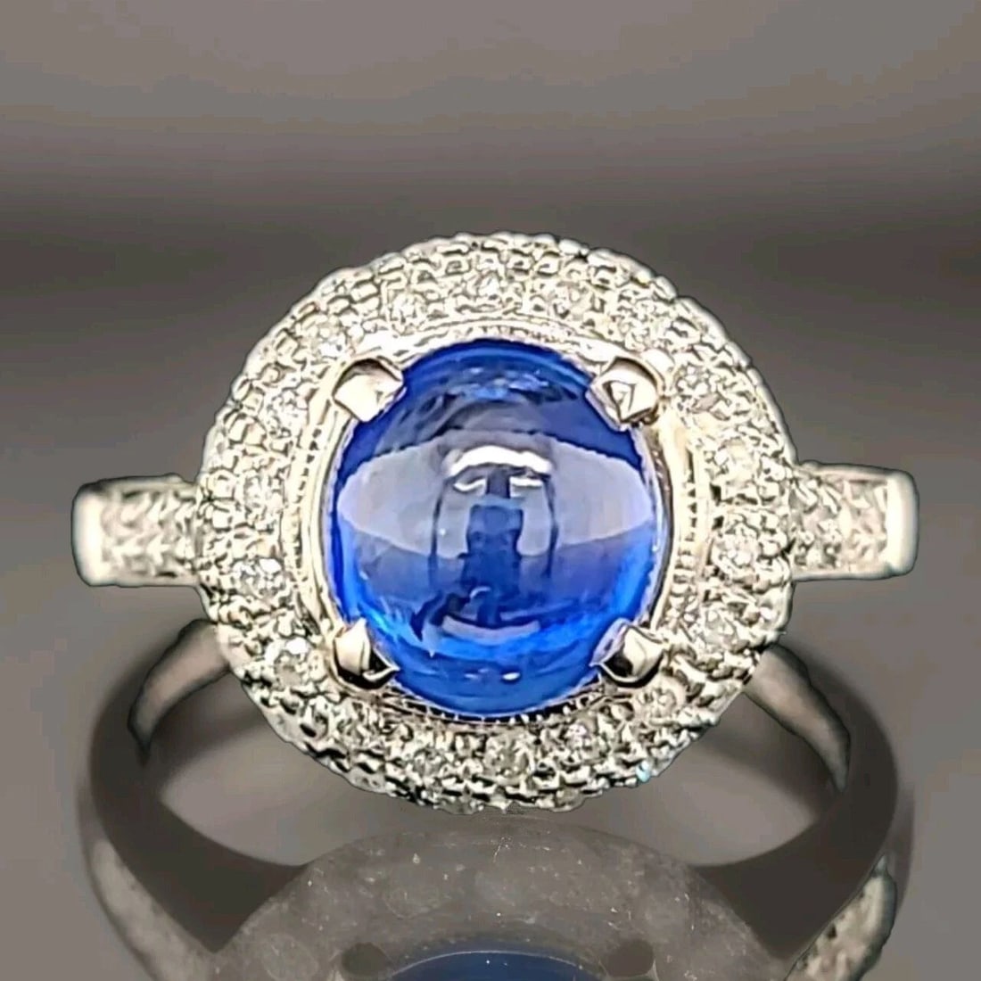18K White Gold Engagement Ring 2.57CT.Natural Blue Sapphire Cabochon Shape: 18K WHITE GOLD ENGAGEMENT RING 2.57CT.NATURAL BLUE SAPPHIRE CABOCHON SHAPE This exquisite 18K white gold engagement ring features a stunning 2.57-carat natural blue sapphire in a cabochon shape. The r