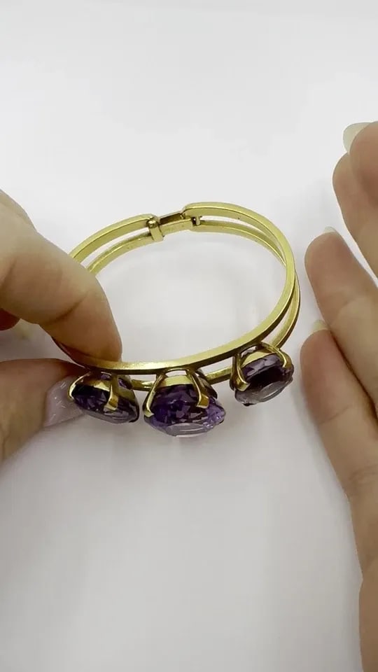 VINTAGE HERMÈS 18K GOLD AMETHYST CLAMPER BRACELET: VINTAGE HERMÈS 18K GOLD AMETHYST CLAMPER BRACELET A striking vintage Hermès cuff bracelet crafted in 18K yellow gold, showcasing three vivid oval-cut amethysts in beautifully balanced prong settings