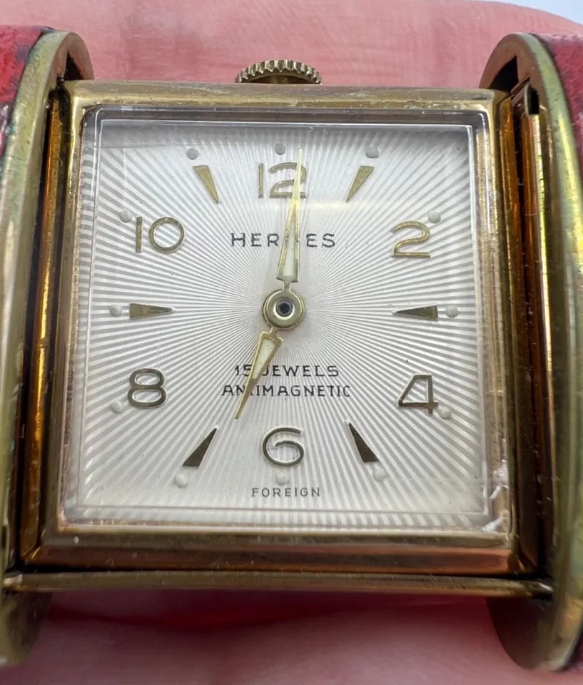 VINTAGE HERMES TRAVEL WATCH C.1960S: VINTAGE HERMES TRAVEL WATCH C.1960S A rare time piece by Hermes, a vintage travel watch. The watch set ina red leather case equipped with a slide opening mechanism. The face is square shape, with a wh