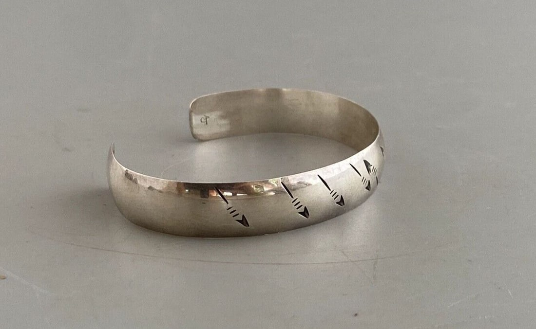 NAVAJO STERLING SILVER CHISELLED BRACELET - ARROWS - SIGNED AJ - 6 1/2": NAVAJO STERLING SILVER CHISELLED BRACELET - ARROWS - SIGNED AJ - 6 1/2" Item Description: This Navajo silver bracelet has an interesting design of arrows moving in opposing directions on opposite side