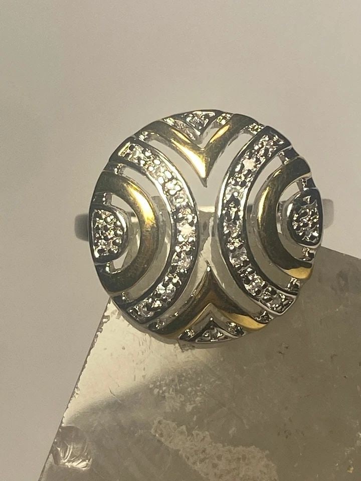 GEOMETRIC RING COCKTAIL CZ'S STERLING SILVER WOMEN: GEOMETRIC RING COCKTAIL CZ'S STERLING SILVER WOMEN Geometric ring cocktail cz's sterling silver women Unknown type of gold over sterling silver Size 5.25 Weight 5.2g Length. 3/4" Width. 3/4" Thinnest 