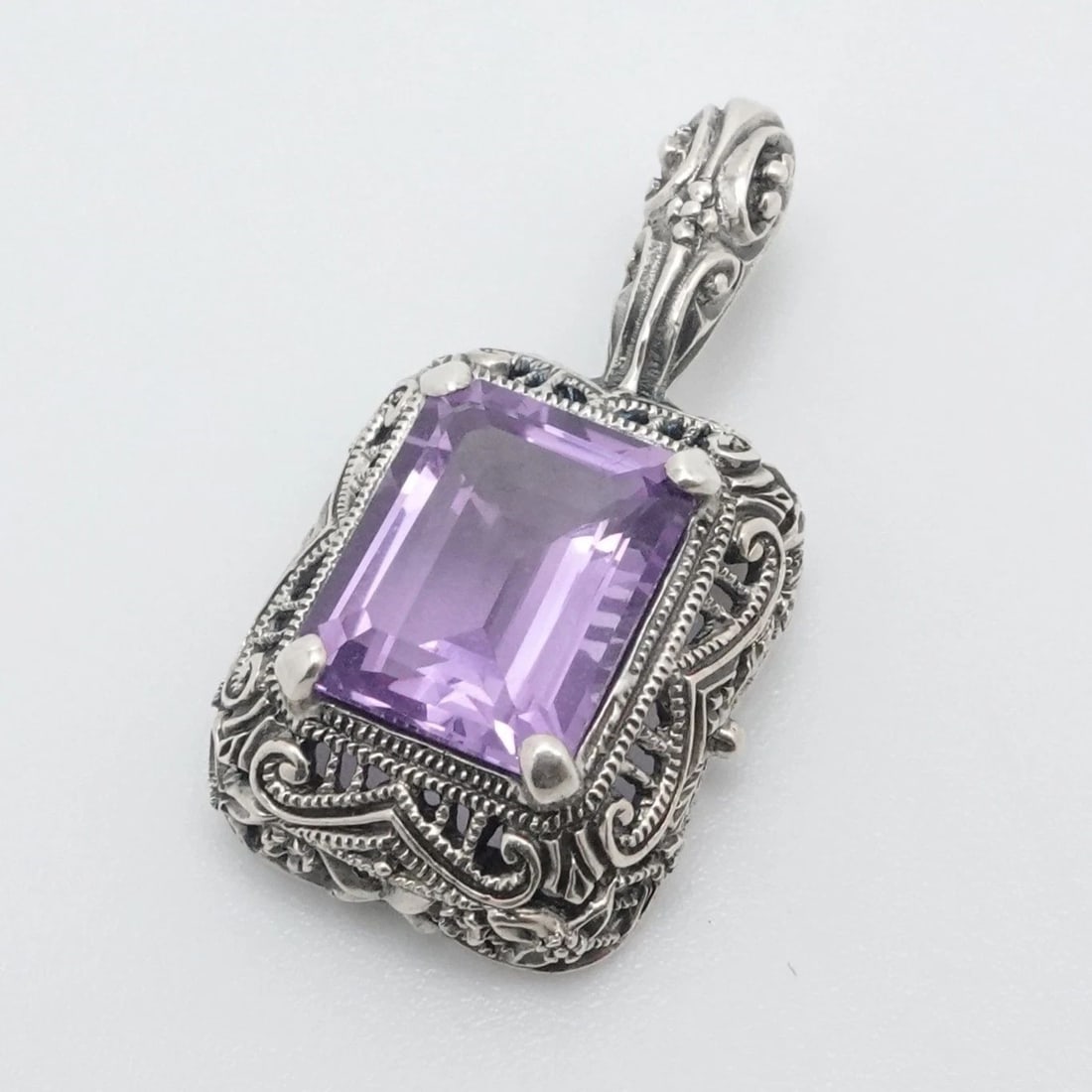 STERLING SILVER FILIGREE EMERALD CUT AMETHYST SMALL PENDANT 1": STERLING SILVER FILIGREE EMERALD CUT AMETHYST SMALL PENDANT 1" Sterling Silver Filigree Style Emerald Cut Amethyst Small Pendant Length - 1" Width - 14mm Bail Height - 5mm Bail With - 2mm Gemstone Siz