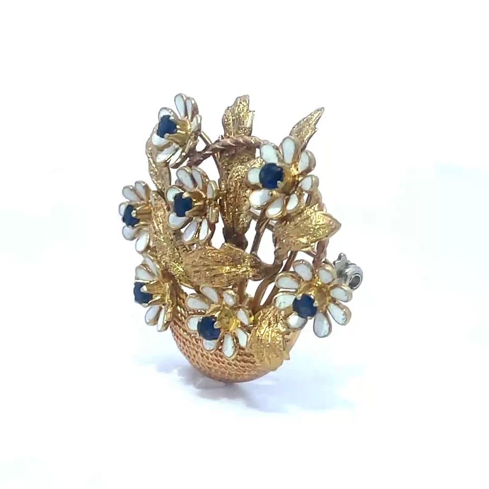 MERRIN GOLD ENAMEL BROOCH SAPPHIRE 18K YELLOW ITALY FLOWER BASKET: The adorable brooch is by designer Merrin, it is crafted from 18k yellow gold featuring a textured basket filled with long stem flower with leaves. Each flower has white enamel petals with a sapphire 