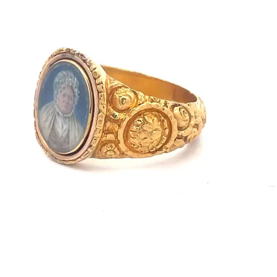 EDWARDIAN 22K GOLD RING PAINTED WOMAN PORTRAIT DEEP RELIEF FLORAL STYLE: The product is a vintage 22k gold ring from the Edwardian era, featuring an oval shaped painted woman portrait. The wide shank and tapered band has deep relief floral design. This unique ring is perfe
