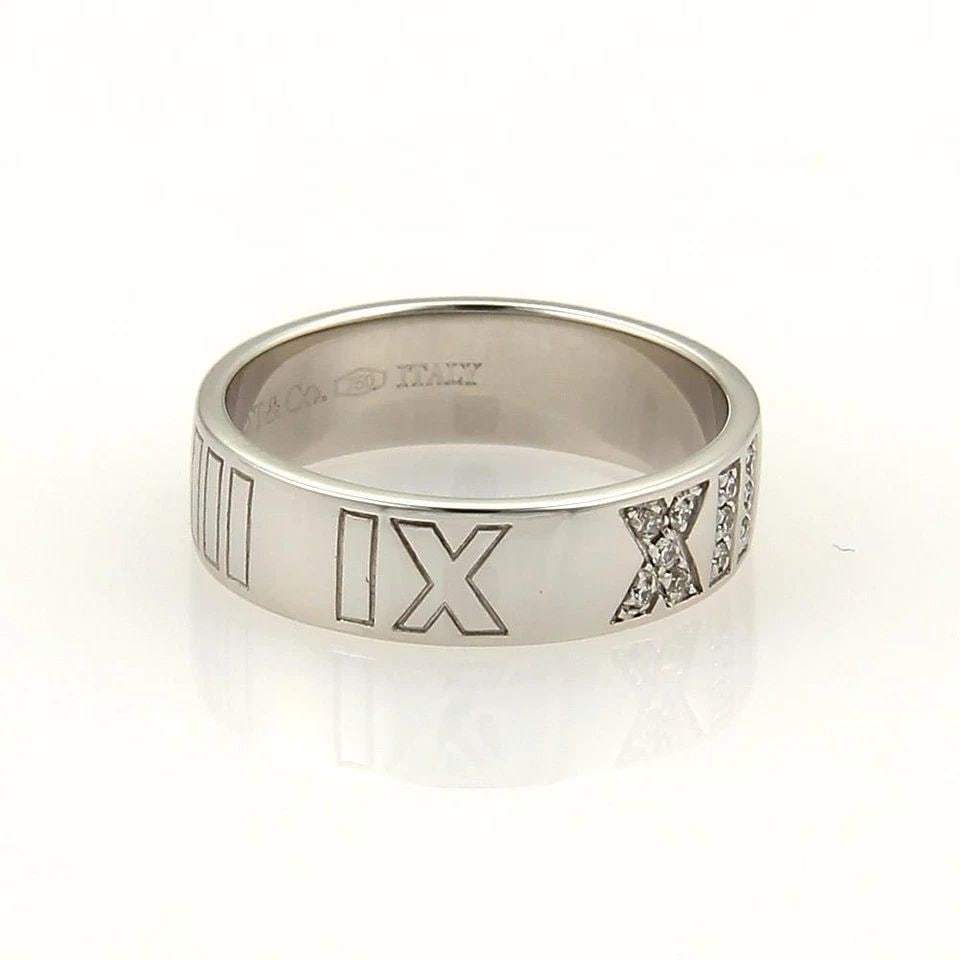 TIFFANY & CO.ATLAS GOLD RING DIAMONDS ROMAN NUMERAL 18K WHITE BAND SIZE 5: TIFFANY & CO.ATLAS GOLD RING DIAMONDS ROMAN NUMERAL 18K WHITE BAND SIZE 5 TIFFANY & CO.ATLAS GOLD RING DIAMONDS ROMAN NUMERAL 18K WHITE BAND SIZE 5 The Tiffany & Co. Atlas gold ring is a luxurious pie