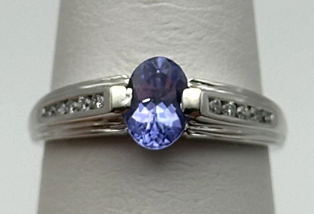 14K WHITE GOLD RING WITH TANZANITE AND 0.10CTW DIAMONDS (SIZE 7) 2.7 GRAM: 14k White Gold Ring with Tanzanite and 0.10cts of Diamonds Condition: Used Material: 14k White Gold Ring Size: 7 Weight: 2.7 grams Top Width: 6.8mm Bottom Width: 1.1mm Stone Info: Oval cut Tanzanite t