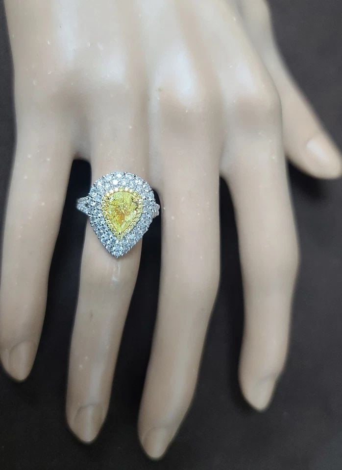 18K WHITE GOLD ENGAGEMENT RING 2.42CT. NATURAL FANCY YELLOW DIAMOND PEAR SHAPE: 18K WHITE GOLD ENGAGEMENT RING 2.42CT. NATURAL FANCY YELLOW DIAMOND PEAR SHAPE This stunning 18k white gold engagement ring features a 1.05ct pear-shaped natural fancy yellow diamond, surrounded by sp