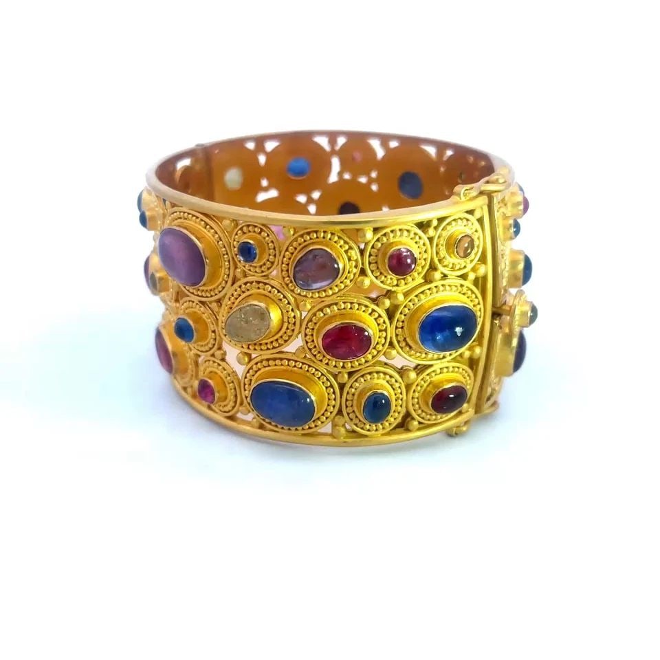 CAROLYN TYLER GOLD WIDE BRACELET 22K 18K YELLOW MULTICOLOR GEMS 107.9G: CAROLYN TYLER GOLD WIDE BRACELET 22K 18K YELLOW MULTICOLOR GEMS 107.9G This large stunning bracelet is by Carolyn Tyler, it is 22k and 18k yellow gold featuring an oval-shaped wide band with assorted 