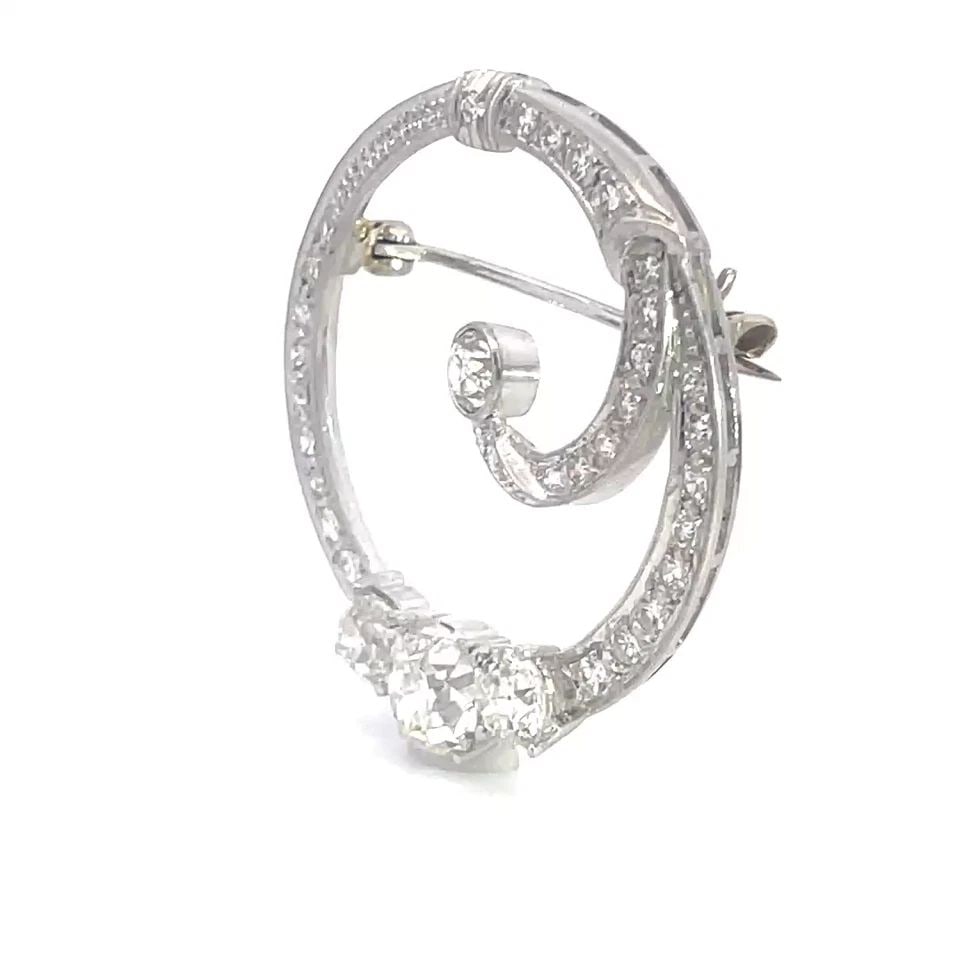 ART DECO DIAMOND BROOCH PLATINUM 2CT EUROPEAN CUT CURLED WREATH DESIGN: This magnificent eye-catching Art Deco brooch features a stunning design of curled wreath with larger European Cut Oval Diamond as the center stone with a round diamond on each side, all diamonds are 