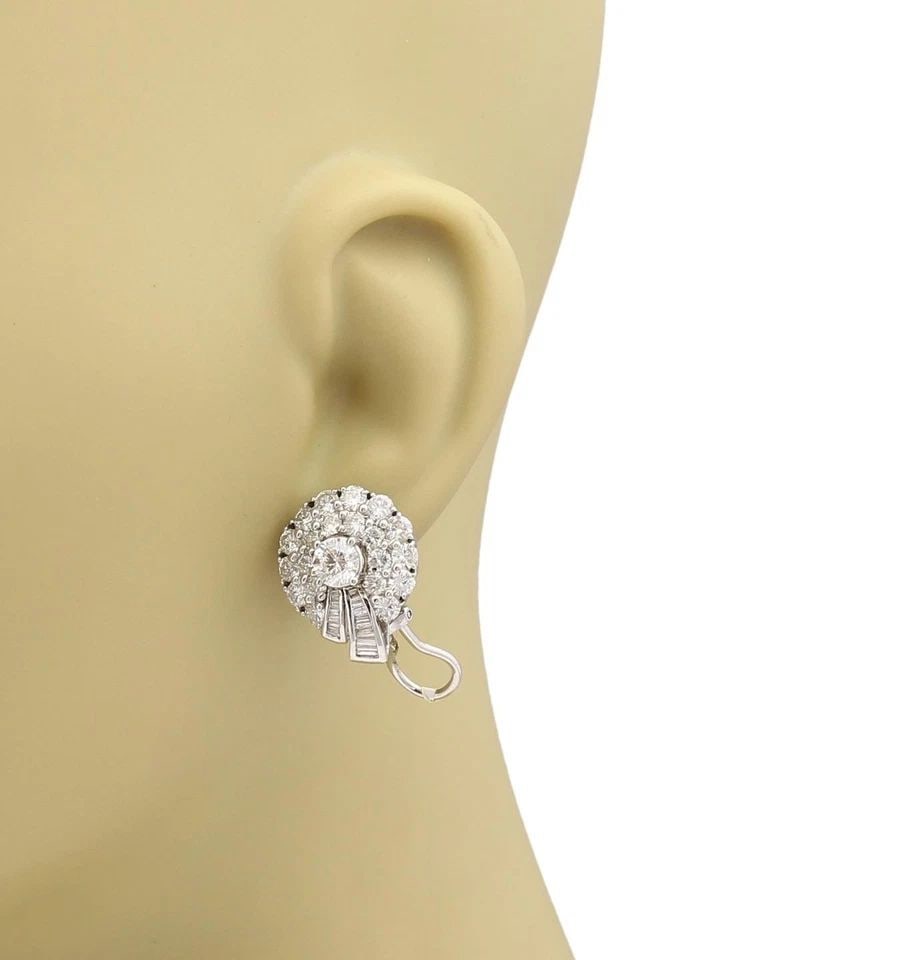 DIAMOND EARRINGS WHITE GOLD 18KT WREATH HUGGIE POST CLIP: DIAMOND EARRINGS WHITE GOLD 18KT WREATH HUGGIE POST CLIP These Diamond Earrings in 18kt White Gold feature a huggie style design with a wreath detail and post clip closure. The stones are round-cut na