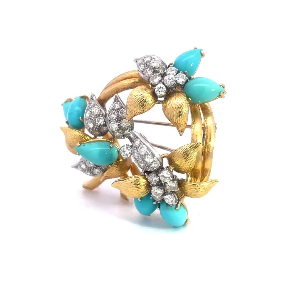 DIAMOND TURQUOISE GOLD BROOCH 18K TWO TONE FLOWER STYLE: DIAMOND TURQUOISE GOLD BROOCH 18K TWO TONE FLOWER STYLE This gorgeous brooch is crafted from 18k yellow and white gold featuring flowers on a double stem round frame, the petals of the flowers are cab