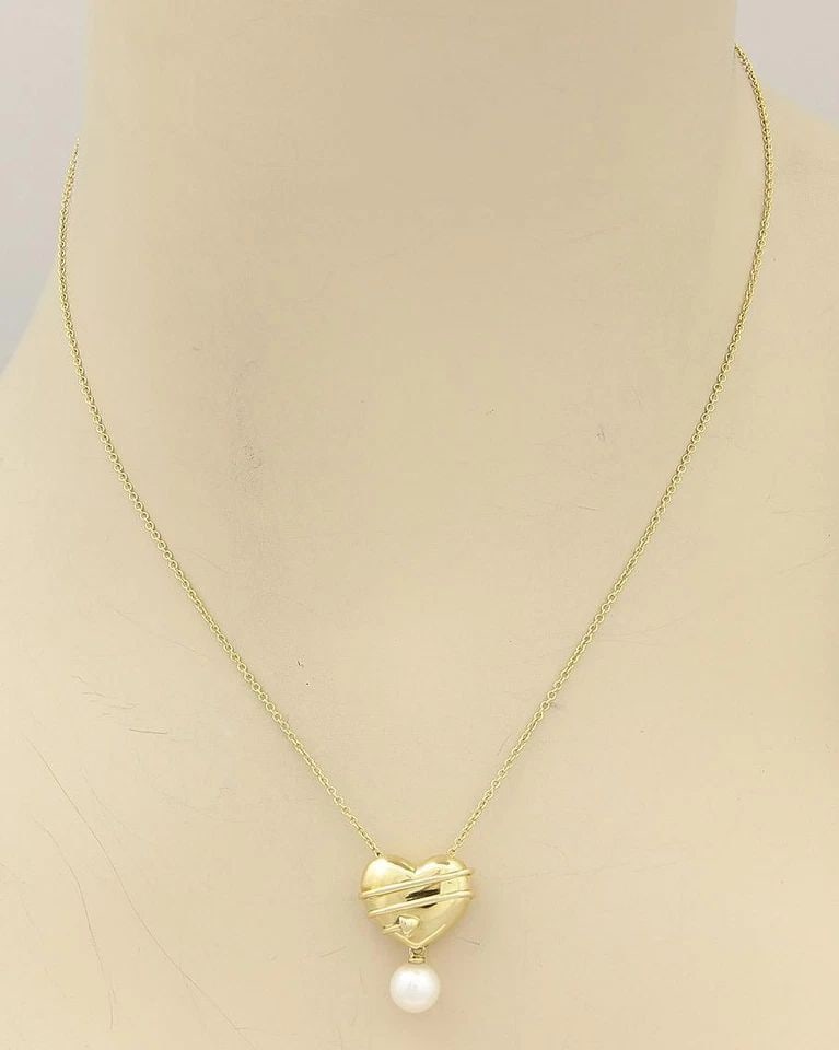 TIFFANY & CO. HEART GOLD NECKLACE PEARL & 18KT YELLOW GOLD CUPID'S ARROW: TIFFANY & CO. HEART GOLD NECKLACE PEARL & 18KT YELLOW GOLD CUPID'S ARROW The Tiffany & Co. Cupid's Arrow Heart necklace is crafted from 18k yellow gold featuring a single pearl dangling from the penda