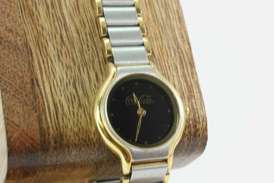 COCA COLA TWO TONE BLACK DIAL EUROPA LADIES WATCH: COCA COLA TWO TONE BLACK DIAL EUROPA LADIES WATCH Description COCA COLA TWO TONE BLACK DIAL EUROPA LADIES WATCH New Battery Installed. In great working condition. Case & band shows sign of wear. Watch