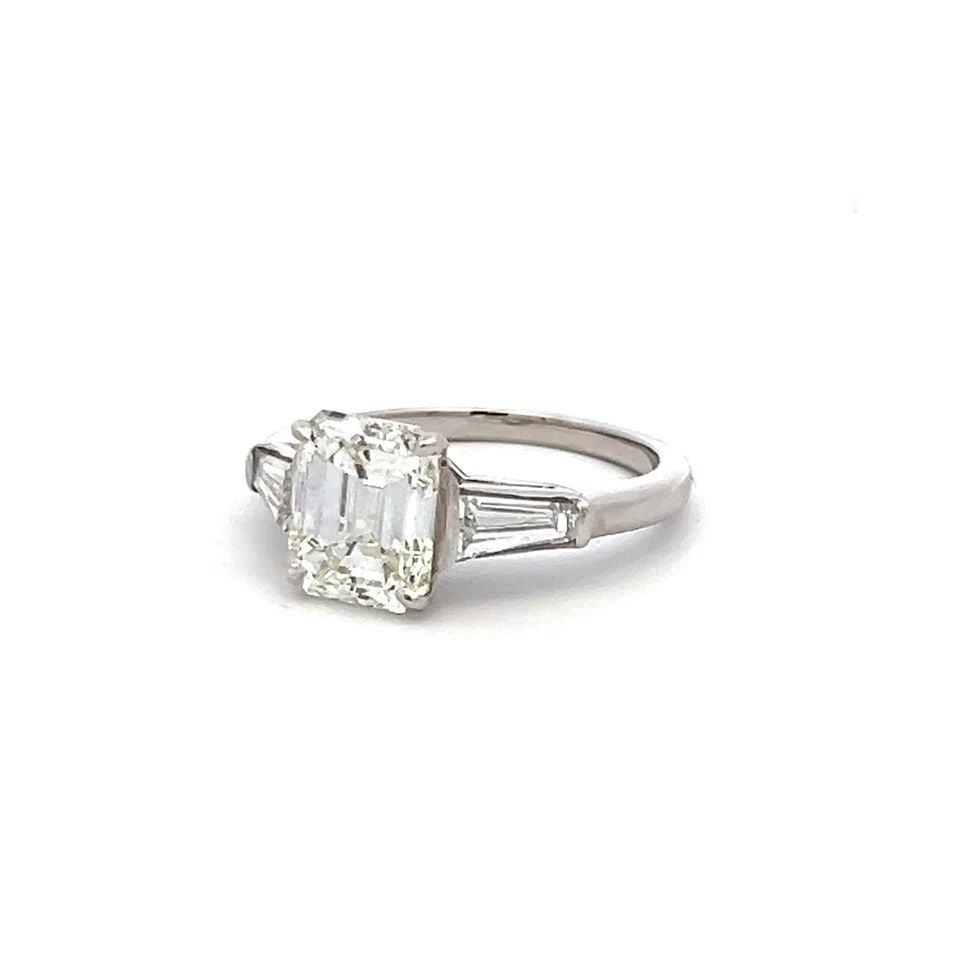 2.40CT EMERALD CUT K SI1 DIAMOND PLATINUM VINTAGE ENGAGEMENT RING: 2.40CT EMERALD CUT K SI1 DIAMOND PLATINUM VINTAGE ENGAGEMENT RING Title: This elegant vintage engagement ring features a striking 2.10 carat emerald cut diamond, graded K color and SI1 clarity, and ce