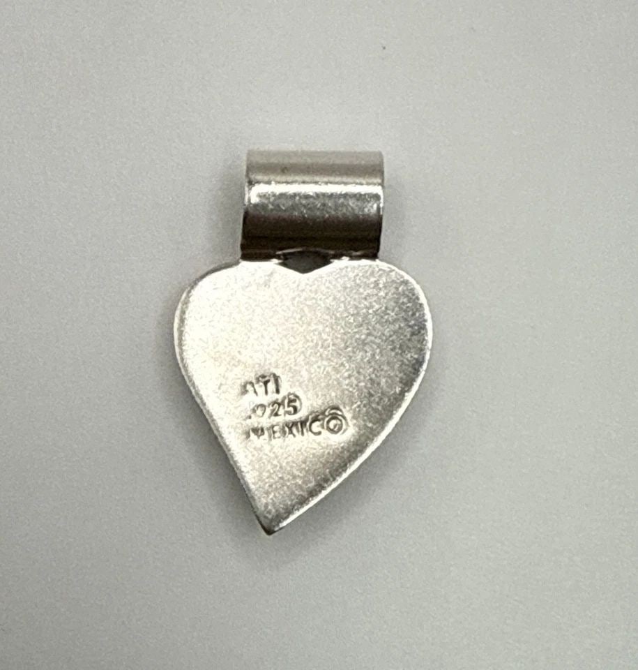 MEXICO ATI STERLING SILVER & PEACH PINK CORAL HEART SHAPED PENDANT 1": MEXICO ATI STERLING SILVER & PEACH PINK CORAL HEART SHAPED PENDANT 1" The product is a 1" pendant made of sterling silver and featuring a peach pink coral stone shaped like a heart. It has a Mexican e