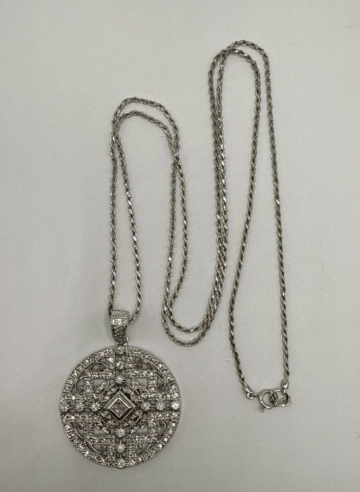 925 ROUND FLORAL DESIGN CZ CRYSTAL PENDANT ON 30" STERLING SILVER ROPE CHAIN: 925 ROUND FLORAL DESIGN CZ CRYSTAL PENDANT ON 30" STERLING SILVER ROPE CHAIN The product is a 925 sterling silver pendant with a floral design featuring colorless cubic zirconium crystals. It comes wi