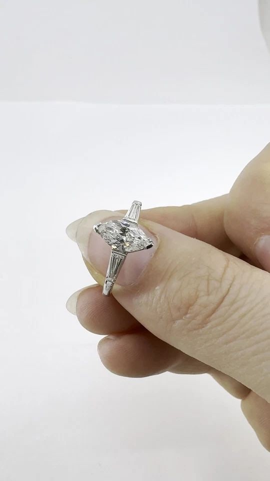 VINTAGE PLATINUM 1.07 CARAT MARQUISE DIAMOND THREE STONE RING: VINTAGE PLATINUM 1.07 CARAT MARQUISE DIAMOND THREE STONE RING KL NGIO Platinum marquise diamond ring, circa 1980s, designed with a 1.07 carat marquise cut center diamond accented by tapered baguette d