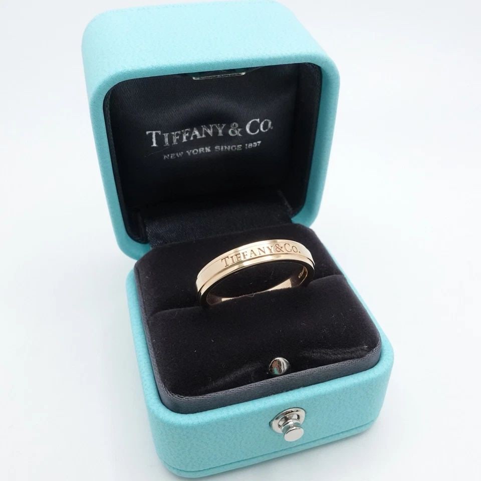 TIFFANY & CO. 18K GOLD BEVELED LOGO 4MM WEDDING BAND RING - SIZE 9 WITH RING BOX: TIFFANY & CO. 18K ROSE GOLD LOGO 4MM WEDDING BAND RING - SIZE 9 BOX Tiffany & Co. 18K Rose Gold Wedding Band Ring Size - 9 Band Width - 4mm Depth - 2mm Thick Total Weight - 6.5 Gram Hallmark - TIFFANY