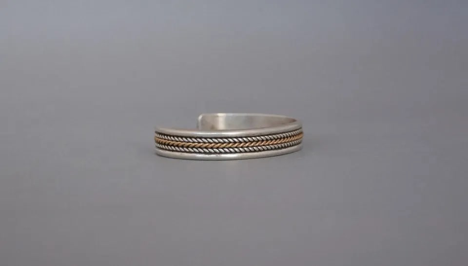 VINTAGE NAVAJO STERLING SILVER WITH 12 KT.GF GOLD BRACELET 3/8" BAND - SIZE 7": VINTAGE NAVAJO STERLING SILVER WITH 12 KT.GF GOLD BRACELET 3/8" BAND - SIZE 7" This bracelet has been beautifully crafted by Navajo silversmith Daniel Mike. It has 2 rows of twisted sterling silver wi