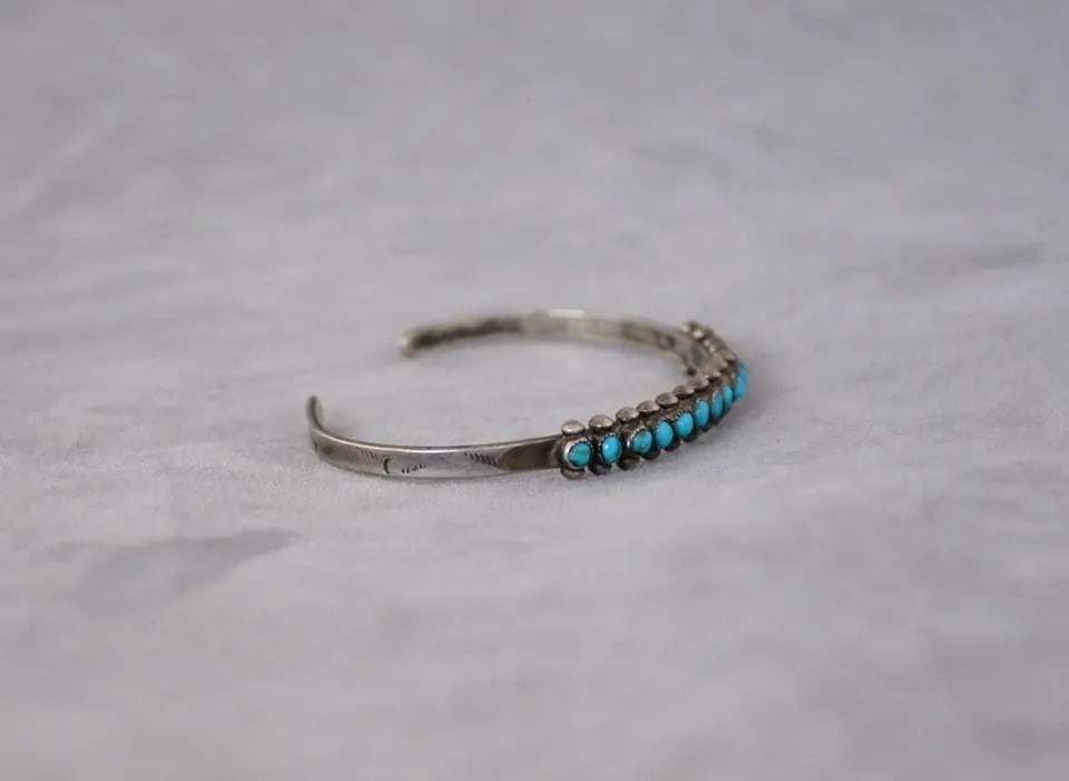 OLD PAWN ZUNI STERLING SILVER TURQUOISE ROW BRACELET - 14 STONES - 6 1/4": OLD PAWN ZUNI STERLING SILVER TURQUOISE ROW BRACELET - 14 STONES - 6 1/4" Old pawn Zuni sterling silver row bracelet has been set with 14 turquoise stones. The front of the bracelet is 1/4" tall. The 