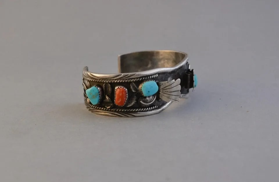VINTAGE NAVAJO STERLING SILVER WATCHBAND BRACELET - TURQUOISE CORAL - 6 1/2": VINTAGE NAVAJO STERLING SILVER WATCHBAND BRACELET - TURQUOISE CORAL - 6 1/2" This vintage Navajo silver watchband cuff bracelet has 4 turquoise stones with 2 pieces of coral and silver applique. The b