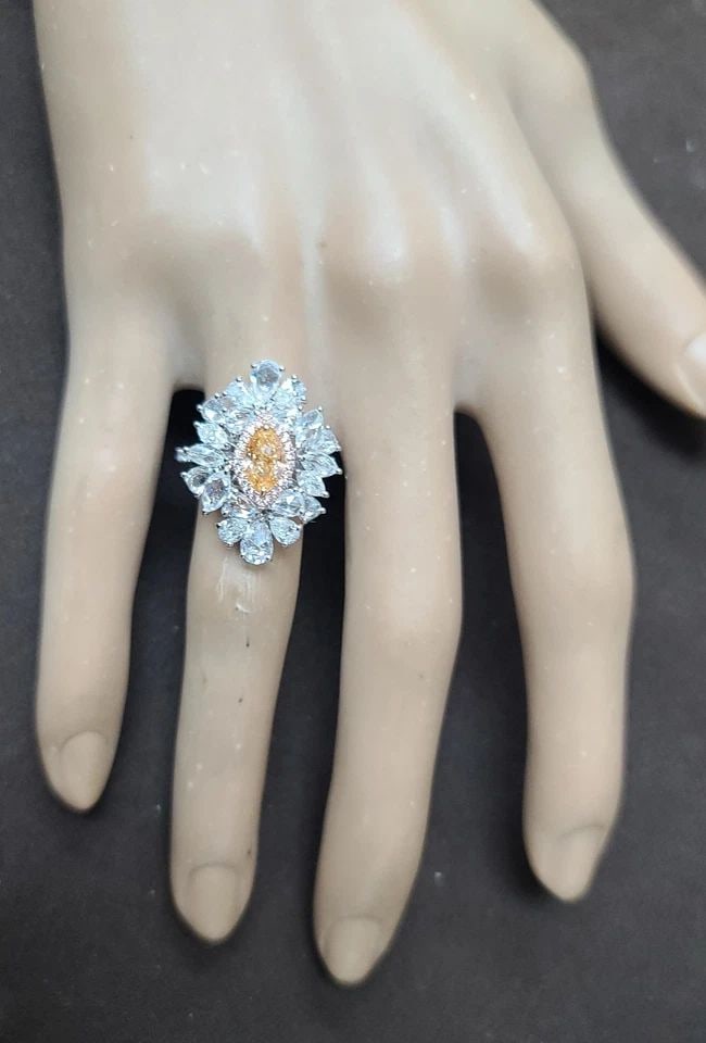 18K WHITE GOLD STATEMENT RING 0.85CT.NATURAL FANCY ORANGE DIAMOND MARQUISE CUT: 18K WHITE GOLD STATEMENT RING 0.85CT.NATURAL FANCY ORANGE DIAMOND MARQUISE CUT This stunning 18k white gold ring is a true statement piece. The marquise cut natural fancy orange diamond is the star of