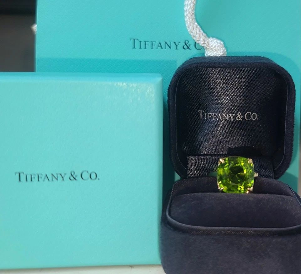 10.38CT. TIFFANY & CO 18K YELLOW GOLD RING NATURAL PERIDOT CUSHION CUT GIA CERT: 10.38CT. TIFFANY & CO 18K YELLOW GOLD RING NATURAL PERIDOT CUSHION CUT GIA CERT Tiffany & Co 10.38carat natural green peridot set in 18k yellow gold ring. Peridot weight 10.38ct. Size 12.9x12.8mm GIA 