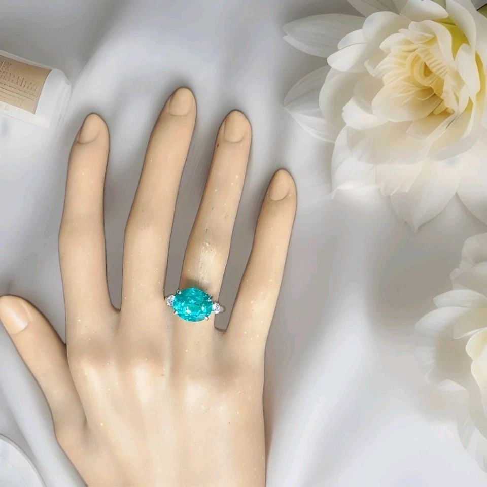 VINTAGE PLATINUM ENGAGEMENT RING 7.27CT. BLUE NEON TOURMALINE OVAL SHAPE: VINTAGE PLATINUM ENGAGEMENT RING 7.27CT. BLUE NEON TOURMALINE OVAL SHAPE This exquisite vintage ring showcases a 7.27-carat oval-cut lab-grown blue tourmaline (12 × 10 mm) with a vibrant neon blue co