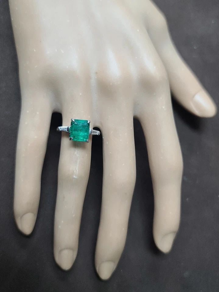 VINTAGE 14K WHITE GOLD ENGAGEMENT RING 2.74CT. NATURAL GREEN EMERALD SHAPE: VINTAGE 14K WHITE GOLD ENGAGEMENT RING 2.74CT. NATURAL GREEN EMERALD CUT This Vintage 14K White Gold Ring features a stunning 2.74CT Natural Green Emerald Cut Stone, accented by two diamonds. The squa