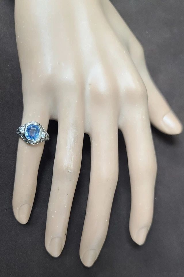 VINTAGE 18K WHITE GOLD ENGAGEMENT RING 1.64CT. NATURAL BLUE SAPPHIRE CUSHION: VINTAGE 18K WHITE GOLD ENGAGEMENT RING 1.64CT. NATURAL BLUE SAPPHIRE CUSHION This vintage 18K white gold engagement ring features a stunning 1.64 carat cushion-cut blue sapphire gemstone, which is set