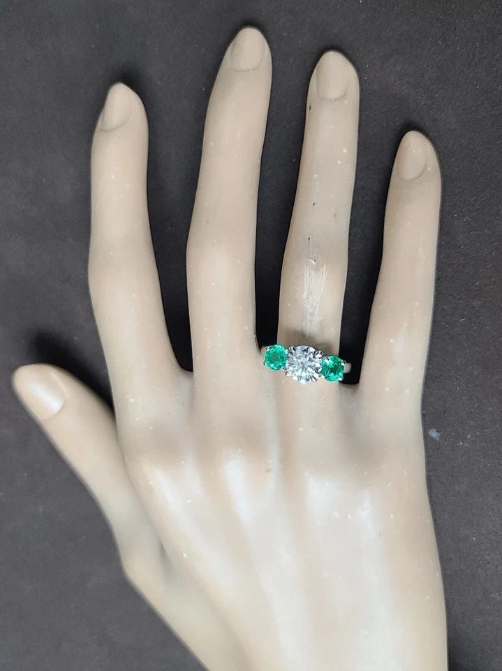 VINTAGE PLATINUM THREE STONES ENGAGEMENT RING 2.19CT DIAMOND GREEN EMERALD: VINTAGE PLATINUM THREE STONES ENGAGEMENT RING 2.19CT DIAMOND GREEN EMERALD This vintage platinum three-stone engagement ring features a dazzling 1.29ct lab-grown diamond in a round shape, surrounded b