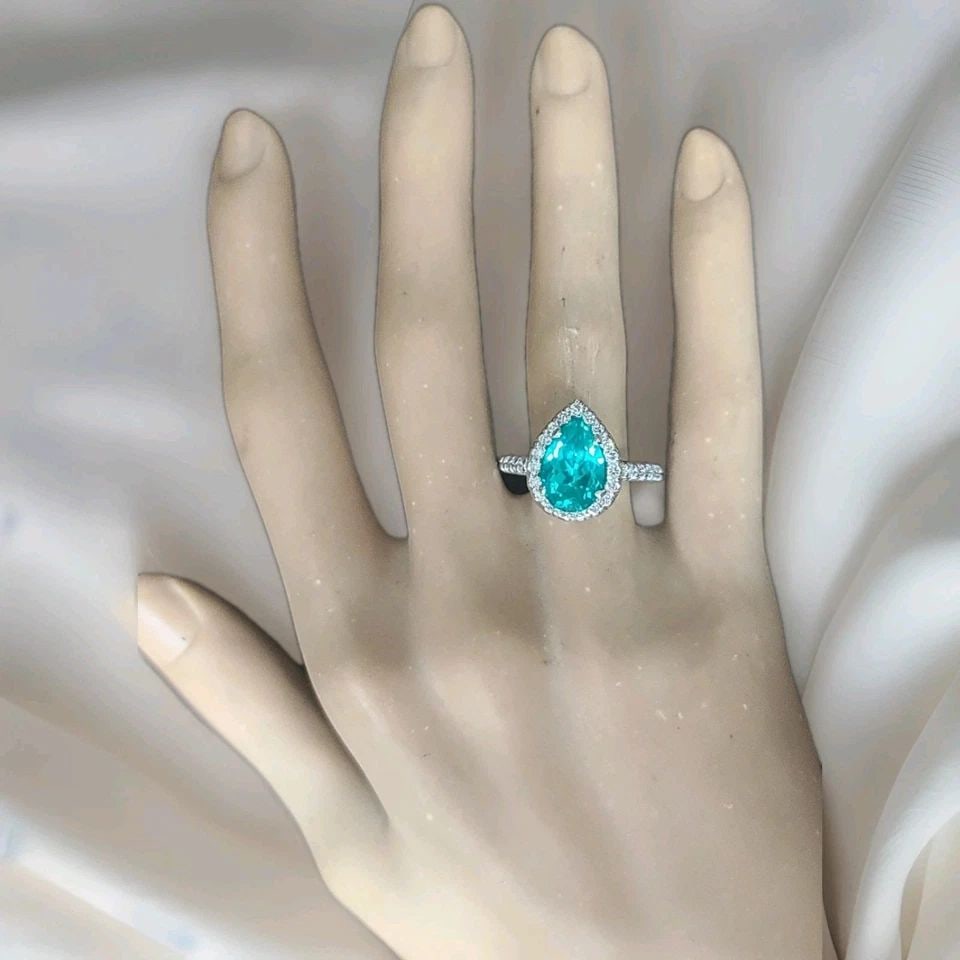 18K WHITE GOLD ENGAGEMENT RING 4.76CT. BLUE NEON TOURMALINE PEAR SHAPE: 18K WHITE GOLD ENGAGEMENT RING 4.76CT. BLUE NEON TOURMALINE PEAR SHAPE Elegant vintage-inspired engagement ring crafted in solid 18K white gold, featuring a stunning pear-shaped lab-grown Neon Blue To