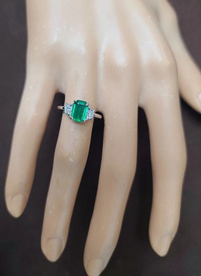 VINTAGE 14K WHITE GOLD ENGAGEMENT RING 1.24CT. NATURAL GREEN EMERALD: VINTAGE 14K WHITE GOLD ENGAGEMENT RING 1.24CT. NATURAL GREEN EMERALD This vintage 14k white gold engagement ring boasts a stunning 1.24ct natural green emerald center stone, flanked by two diamonds. T