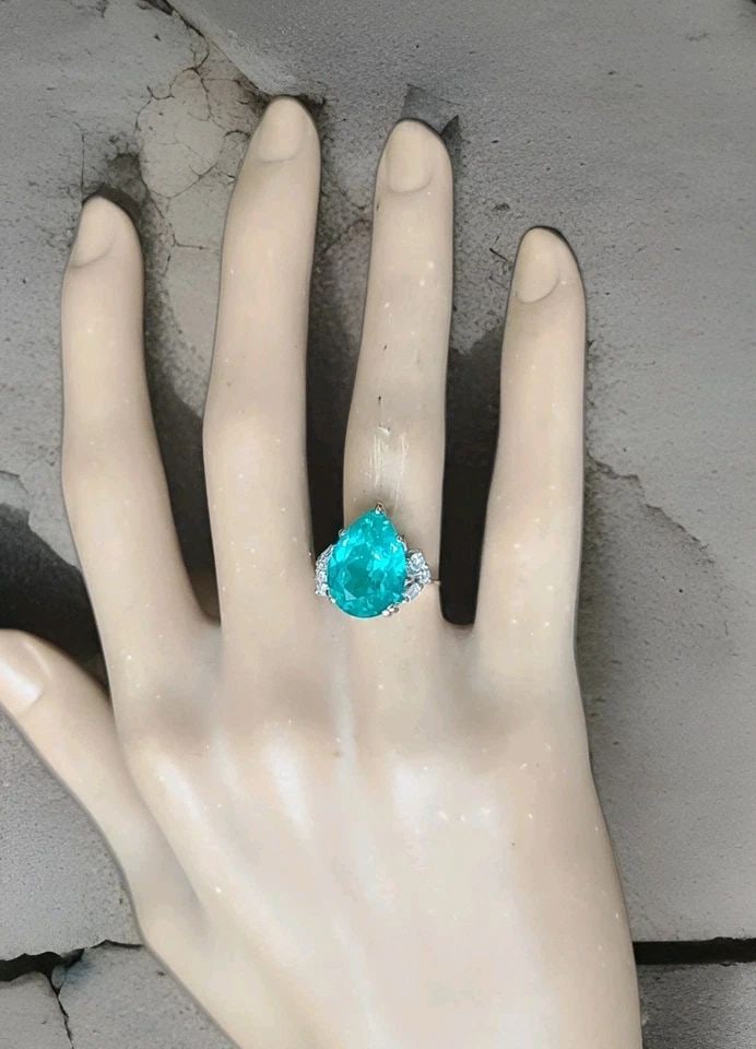 18K WHITE YELLOW GOLD ENGAGEMENT RING 7.89CT. NEON BLUE PARAIBA TOURMALINE PEAR: 18K WHITE YELLOW GOLD ENGAGEMENT RING 7.89CT. LAB GROWN PARAIBA TOURMALINE PEAR This 18K White Gold Engagement Ring features a beautiful lab grown Paraiba Tourmaline pear as the main stone, with a tot