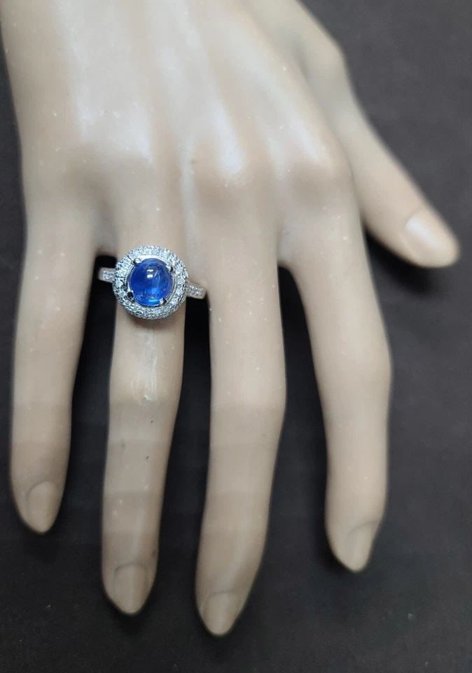 18K WHITE GOLD ENGAGEMENT RING 2.57CT.NATURAL BLUE SAPPHIRE CABOCHON SHAPE: 18K WHITE GOLD ENGAGEMENT RING 2.57CT.NATURAL BLUE SAPPHIRE CABOCHON SHAPE This exquisite 18K white gold engagement ring features a stunning 2.57-carat natural blue sapphire in a cabochon shape. The r