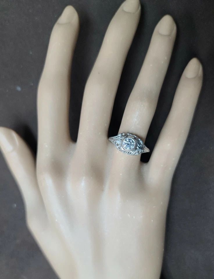 18K WHITE GOLD VINTAGE FILIGREE ENGAGEMENT RING 0.52CT. NATURAL ROUND DIAMOND: 18K WHITE GOLD VINTAGE FILIGREE ENGAGEMENT RING 0.52CT. NATURAL ROUND DIAMOND This is a vintage 18k white gold engagement ring with a filigree design. The ring features a 0.52ct natural round diamond 