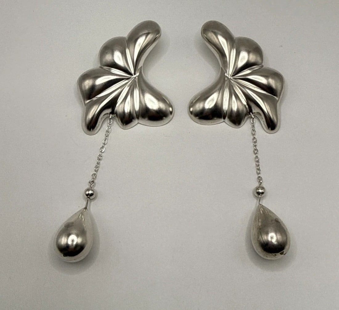 STERLING SILVER HOLLOW MEXICAN DESIGNED EARRING WITH FLOWER LIKE DESIGN 34.8 G: STERLING SILVER HOLLOW MEXICAN DESIGNED EARRING WITH FLOWER LIKE DESIGN 34.8 G These sterling silver earrings feature a traditional Mexican design with a flower-like shape, weighing 34.8 grams. The da