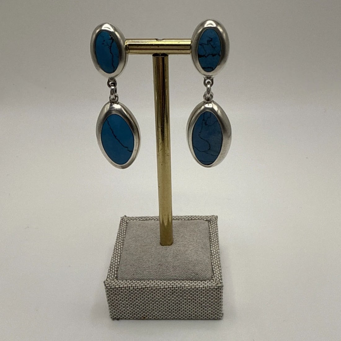 SILVER & TURQUOISE DANGLE EARRINGS: SILVER & TURQUOISE DANGLE EARRINGS SILVER & TURQUOISE DANGLE EARRINGS These Silver & Turquoise Dangle Earrings are crafted with a high purity of 950 silver and feature a stunning blue turquoise stone.