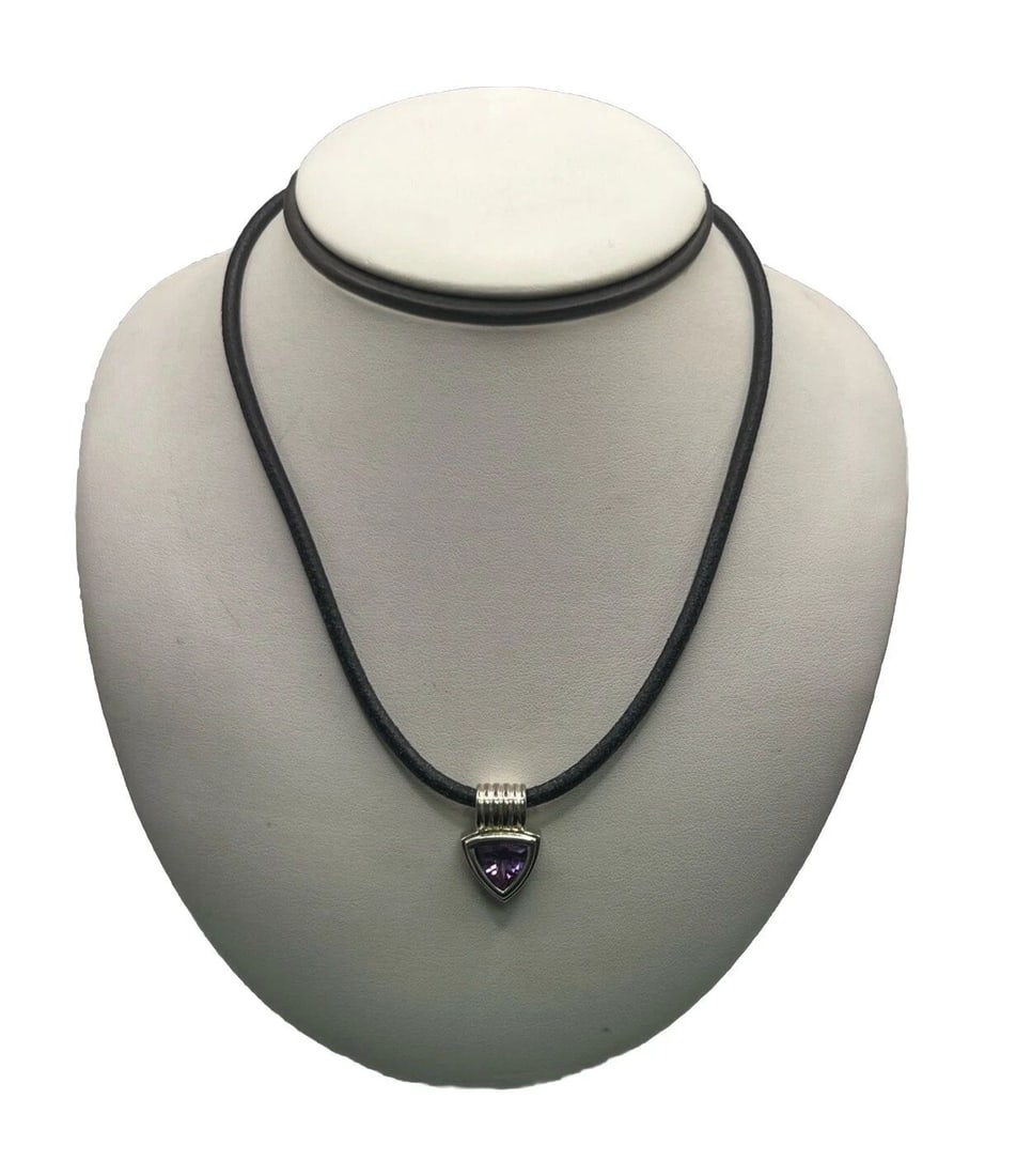 STERLING SILVER PENDANT WITH PURPLE STONE ON 18" BLACK ROPE NECKLACE: STERLING SILVER PENDANT WITH PURPLE STONE ON 18" BLACK ROPE NECKLACE STERLING SILVER PENDANT WITH PURPLE STONE ON 18" BLACK ROPE NECKLACE This sterling silver pendant features a purple triangle-shaped