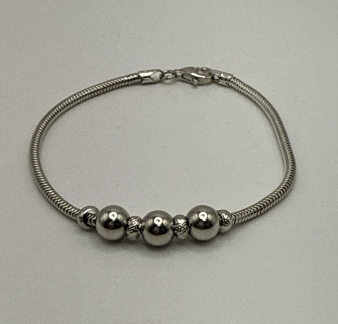 7" STERLING SILVER SNAKE BRACLET WITH BALLS & BEADS 7.5 GRAMS: 7" STERLING SILVER SNAKE BRACLET WITH BALLS & BEADS 7.5 GRAMS This 7" Sterling Silver Snake Bracelet features a unique design with balls and beads, weighing 7.5 grams. The lobster closure ensures a se