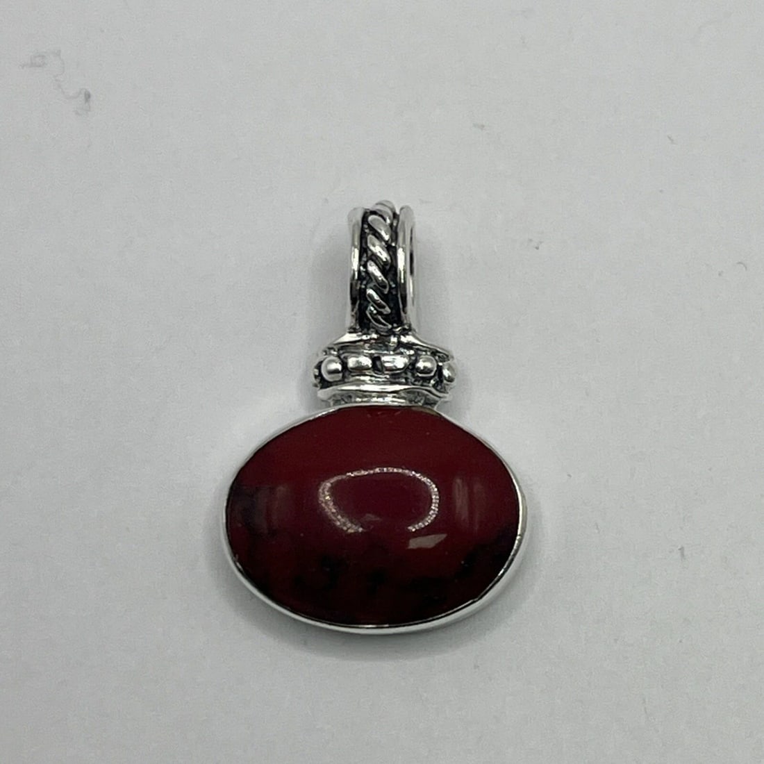 STERLING SILVER WITH RED STONE PENDANT: STERLING SILVER WITH RED STONE PENDANT STERLING SILVER WITH RED STONE PENDANT This is a stunning Sterling Silver pendant featuring an oval-shaped red stone as the main focal point. The pendant is