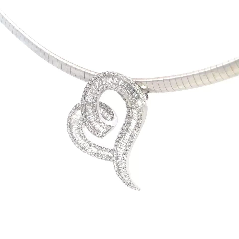 DIAMOND GOLD NECKLACE 18K WHITE OMEGA HEART SLIDE PENDANT: This gorgeous necklace features an 18k white gold omega necklace with a stunning curved heart shape pendant with channel set baguette diamonds and round diamonds decorating along both ends of the hear