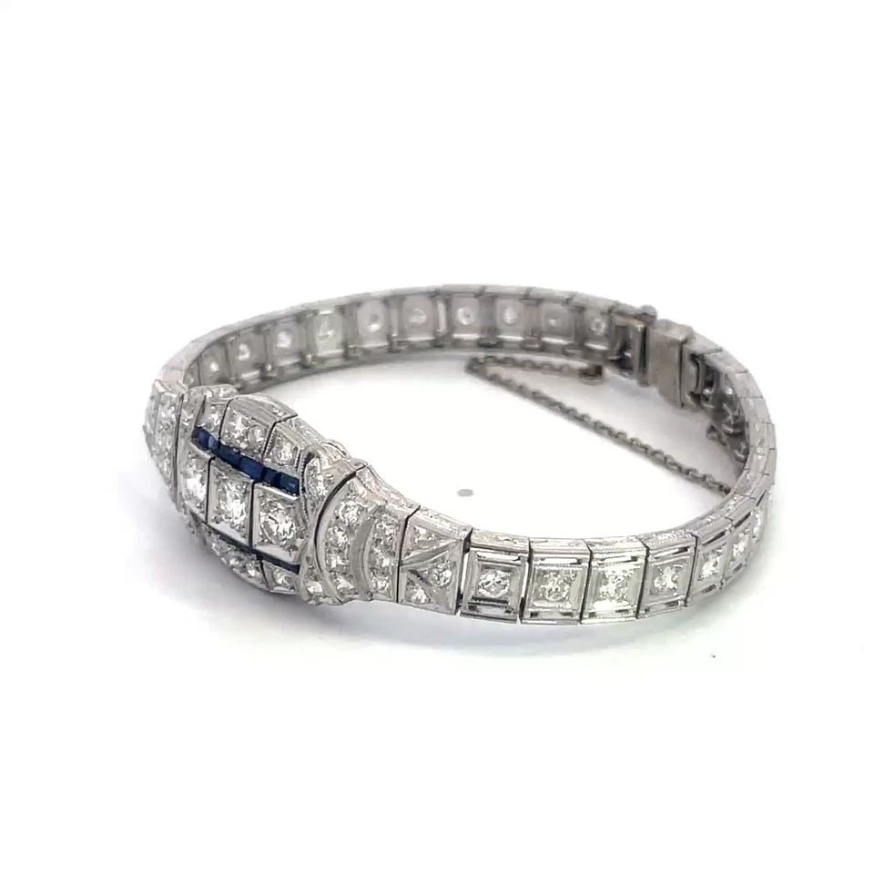 DIAMOND PLATINUM BRACELET GEMSTONE SECTION LINKS MILGRAIN BORDER ART DECO: This beautiful vintage Art Deco diamond platinum bracelet features an intricate centerpiece with larger set round natural diamonds accented with blue gemstones. The links on each side are small rectan