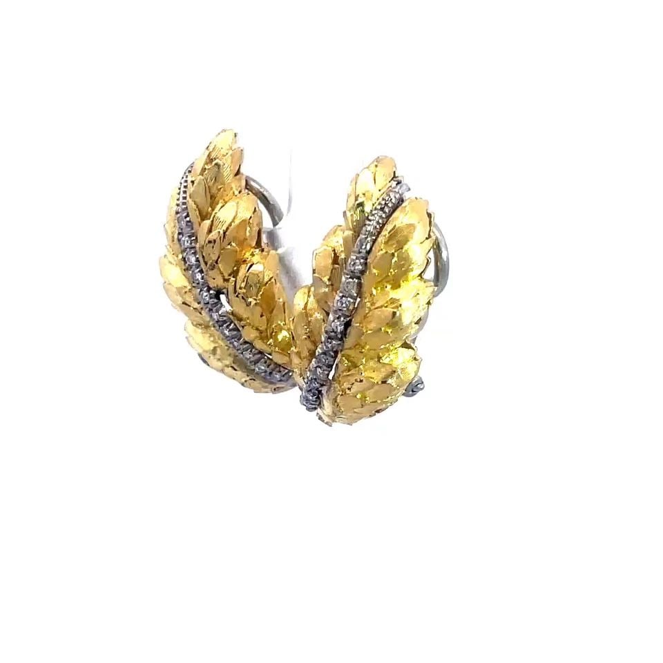 DIAMOND GOLD EARRINGS 18K YELLOW LEAF HUGGIE STYLE ITALY: This lovely pair of earrings are crafted from 18k yellow gold with white gold accent. It features a shiny rough cut long leaf with prong set diamonds on white gold along the center of the leaf. The pa