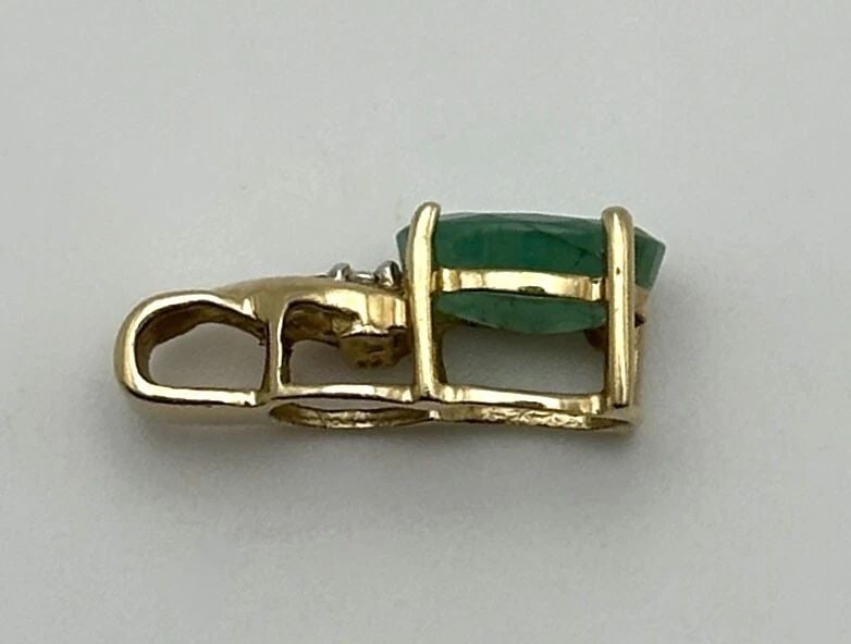 10K GOLD PENDANT WITH NATURAL EMERALD AND 0.01CTS OF DIAMONDS (1 GRAM): 10K GOLD PENDANT WITH NATURAL EMERALD AND 0.01CTS OF DIAMONDS 1.0 GRAM 10k Gold Pendant with Natural Emerald and 0.01cts of Diamonds Condition: Used Material: 10k Yellow Gold Pendant Size: 16mm x 6mm 