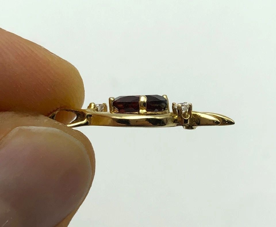 14K GOLD PENDANT WITH GARNET AND 0.08CTW NATURAL DIAMONDS 1.7 GRAMS: 14K GOLD PENDANT WITH GARNET AND 0.08CTS OF DIAMONDS 1.7 GRAMS 14k Gold Pendant with Garnet and 0.08cts of Diamonds Condition: Used Material: 14k Yellow Gold Pendant Size: 25mm x 10mm Total Weight: 1.