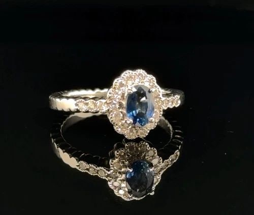 .63CT BLUE SAPPHIRE AND DIAMOND RING IN 14K WHITE GOLD: .63CT BLUE SAPPHIRE AND DIAMOND RING IN 14 WHITE GOLD Elevate your look with this stunning Unisex ring crafted in 14K white gold Featuring a captivating pear cut natural green sapphire weighing 63ct a