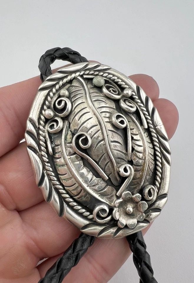 VTG NAVAJO STERLING SILVER DEEP STAMPED OVAL FLORAL FEATHER CONCHO BOLO TIE: VTG NAVAJO STERLING SILVER DEEP STAMPED OVAL FLORAL FEATHER CONCHO BOLO TIE Vtg Navajo Sterling Silver Deep Stamped Oval Floral Feather Concho Bolo Tie Size: Over 2 1/4" Tall by 1 7/8" Wide Weight is 